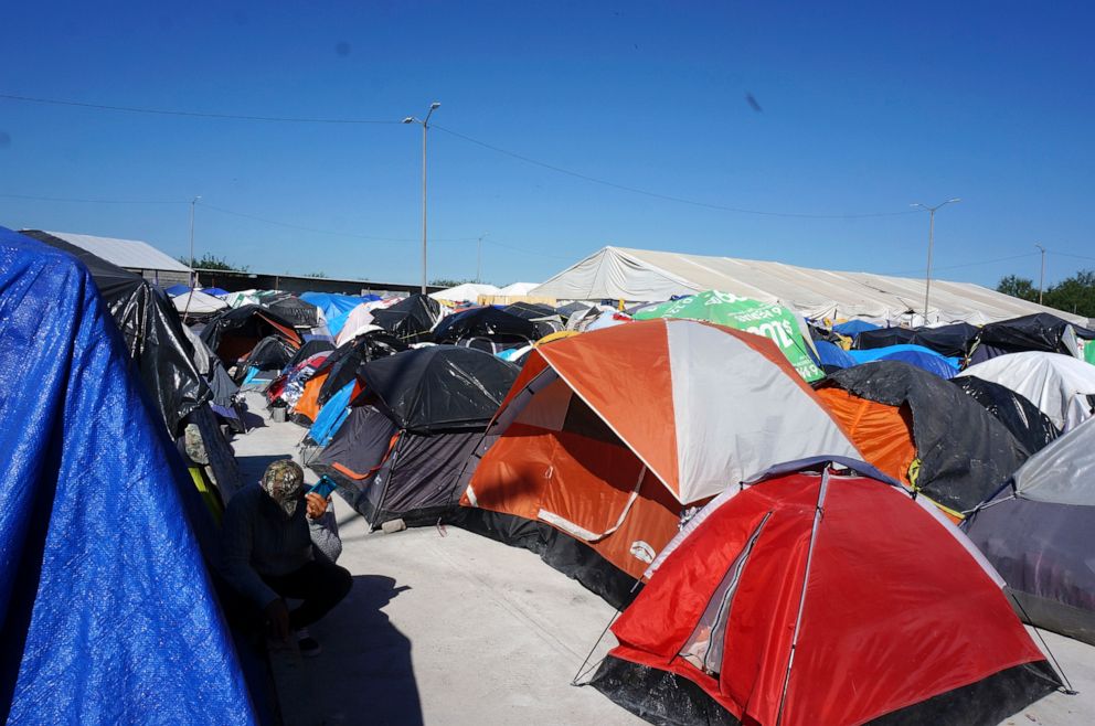 PHOTO: In this file photo from December 15, 2022, a migrant listens to his phone near his tent at the sprawling Senda de Vida 2 open-air shelter in Reynosa, Mexico.