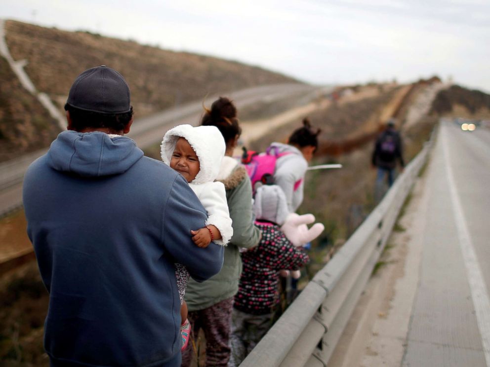 PHOTO: Migrants from Honduras, part of a caravan of thousands from Central America trying to reach the United States, walk next to the border fence as they prepare to cross it illegally in Tijuana, Mexico, Dec. 14, 2018.