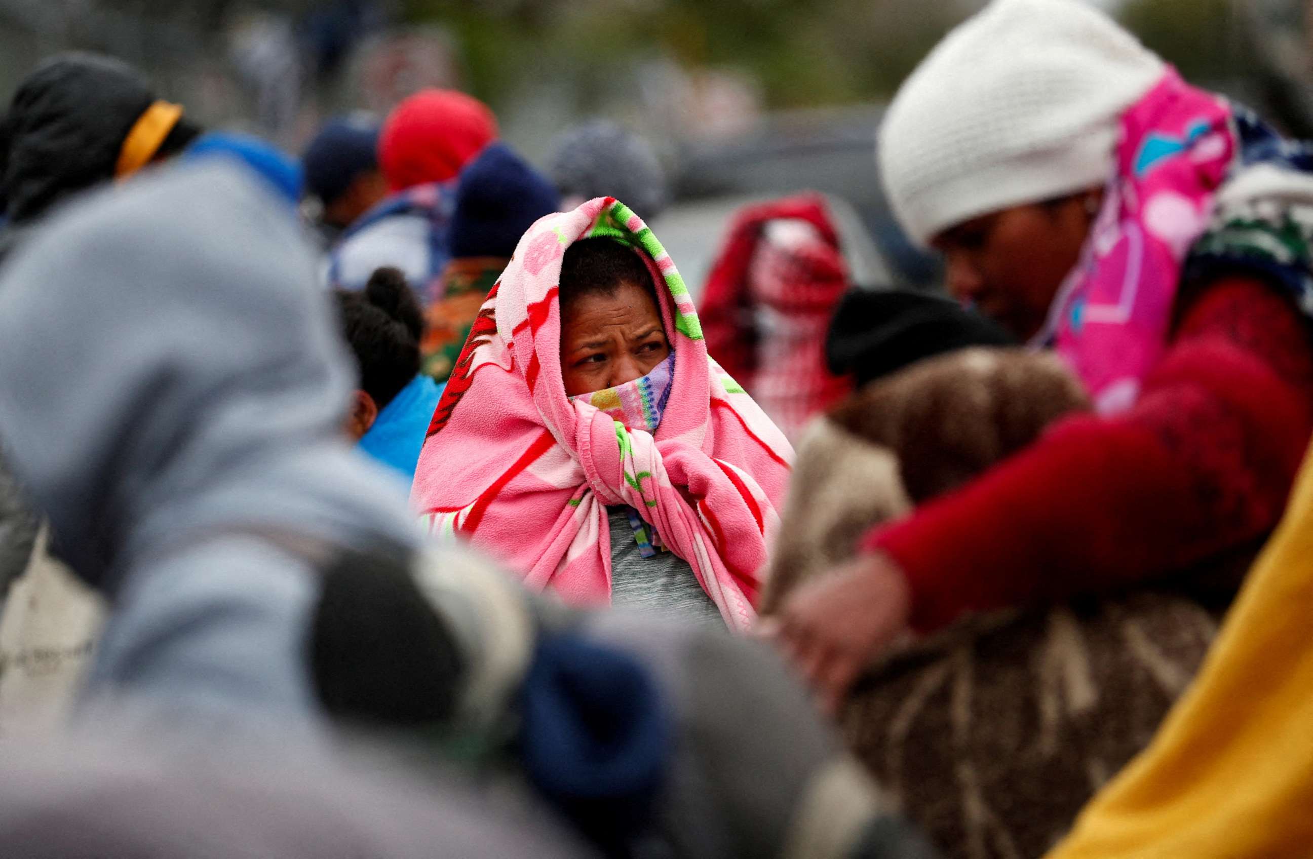 PHOTO: Asylum-seeking migrants stand covered with blankets during a day of high winds and low temperatures at a makeshift encampment near the border between the U.S. and Mexico.