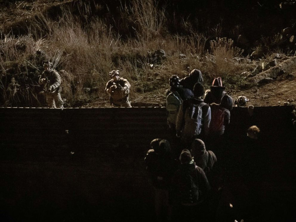   PHOTO: US border protection officers point their guns at migrants as they prepare to cross the fence to enter the United States from Tijuana, Mexico, January 1, 2019. 