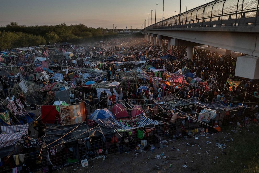 PHOTO: Migrants take shelter along the Del Rio International Bridge at sunset as they await to be processed after crossing the Rio Grande river into the U.S. from Ciudad Acuna in Del Rio, Texas, Sept. 19, 2021.