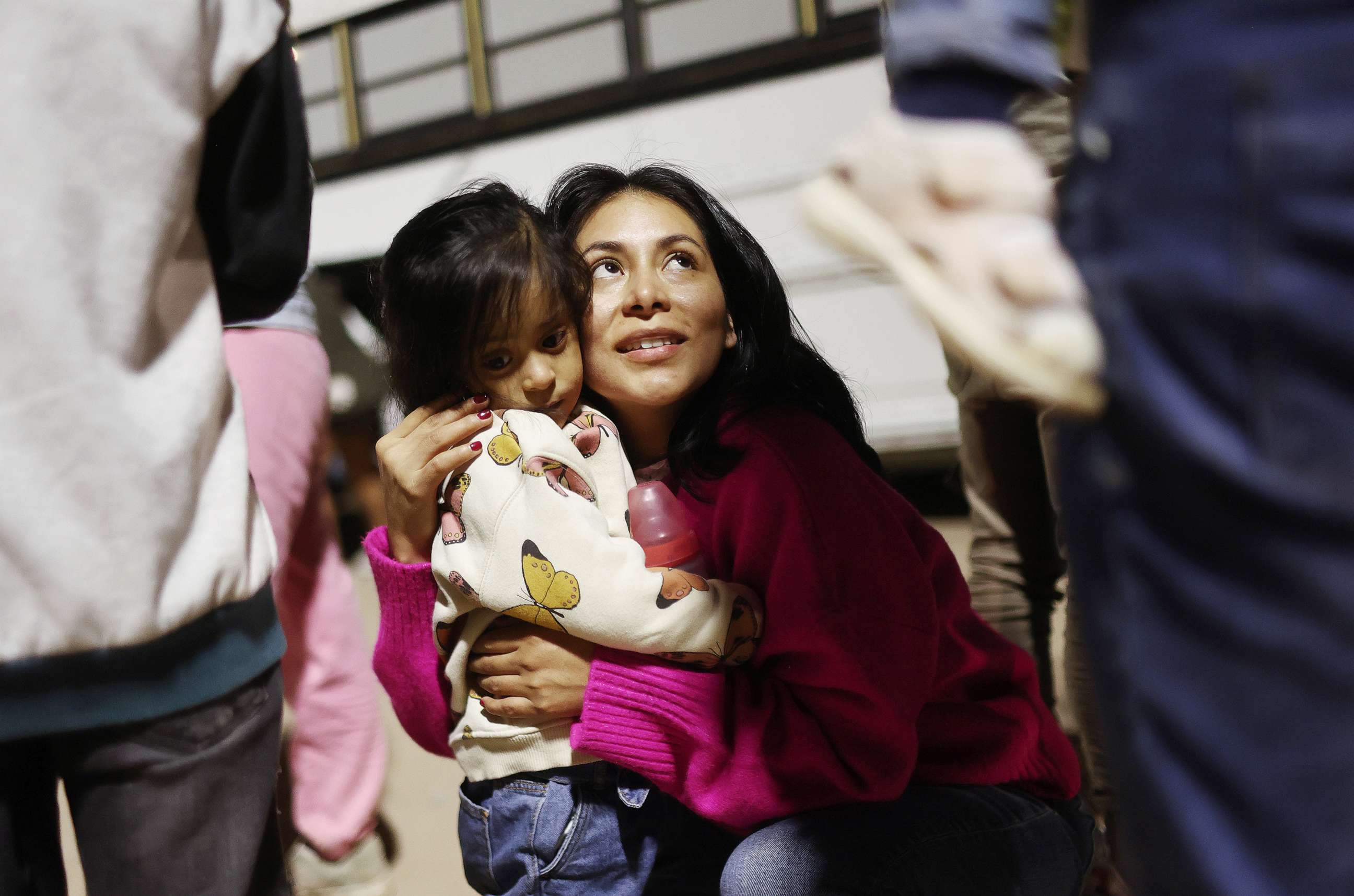 PHOTO: Peruvian immigrant family members, who are seeking asylum in the United States, embrace as they wait to board a bus during processing by U.S. Border Patrol agents after crossing into Arizona from Mexico on May 11, 2023 in Yuma, Ariz.