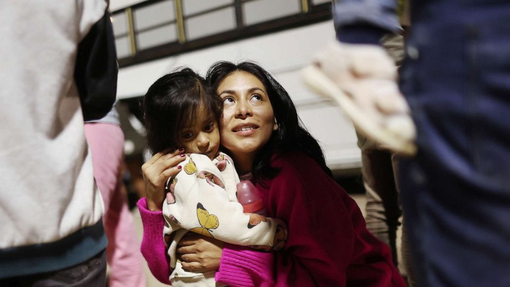 PHOTO: Peruvian immigrant family members, who are seeking asylum in the United States, embrace as they wait to board a bus during processing by U.S. Border Patrol agents after crossing into Arizona from Mexico on May 11, 2023 in Yuma, Ariz.