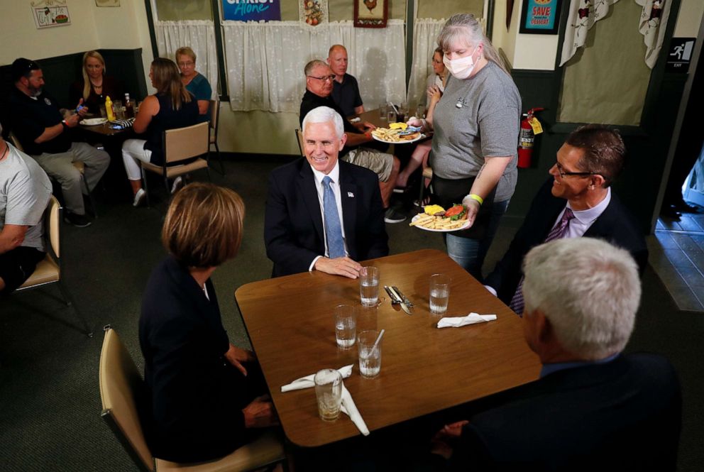 PHOTO: Vice President Mike Pence talks with Iowa Gov. Kim Reynolds, left, her husband Kevin, and state Sen. Randy Feenstra, right, during a lunch stop at Sally's, June 16, 2020, in Forest City, Iowa.