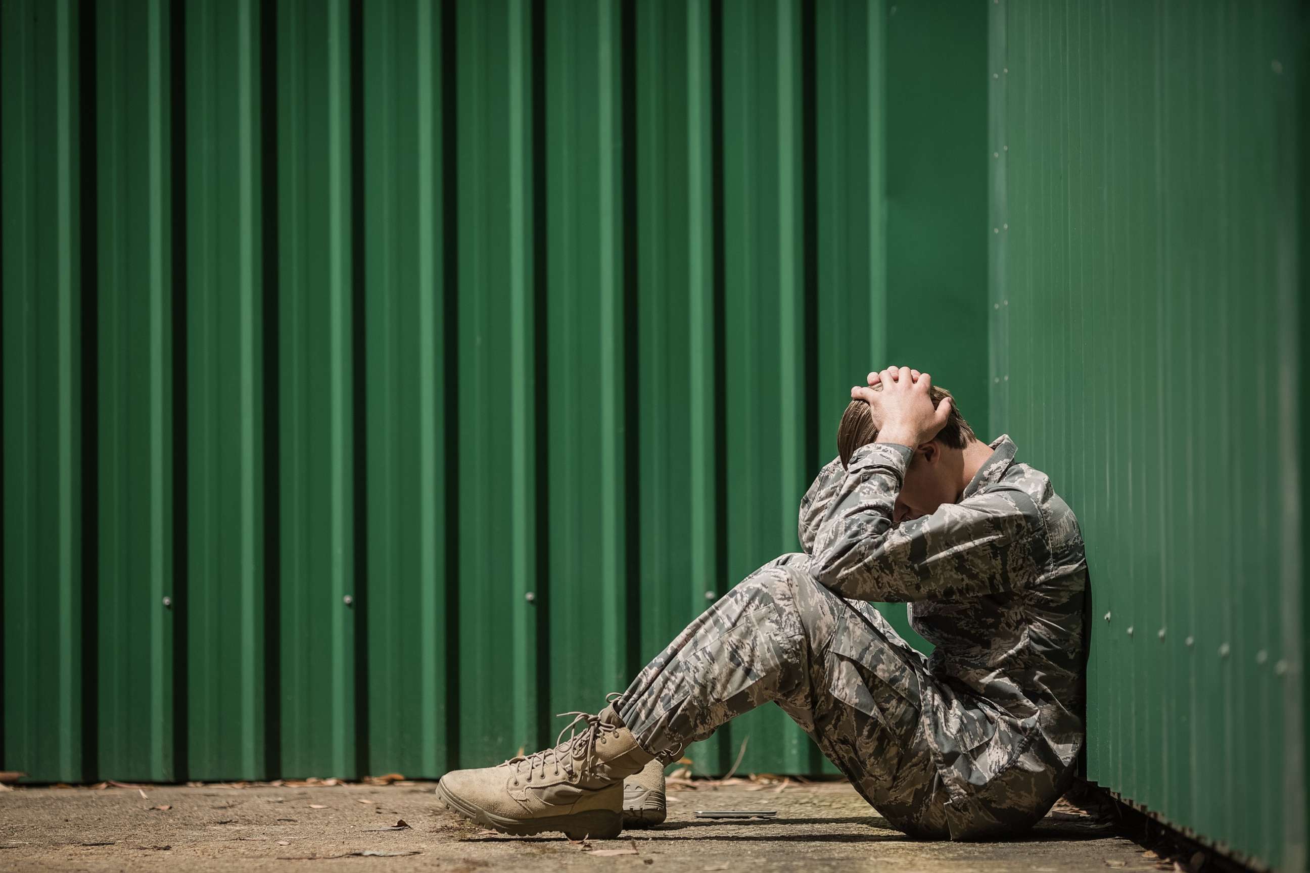 PHOTO: Frustrated military soldier sitting with hands on head in boot camp