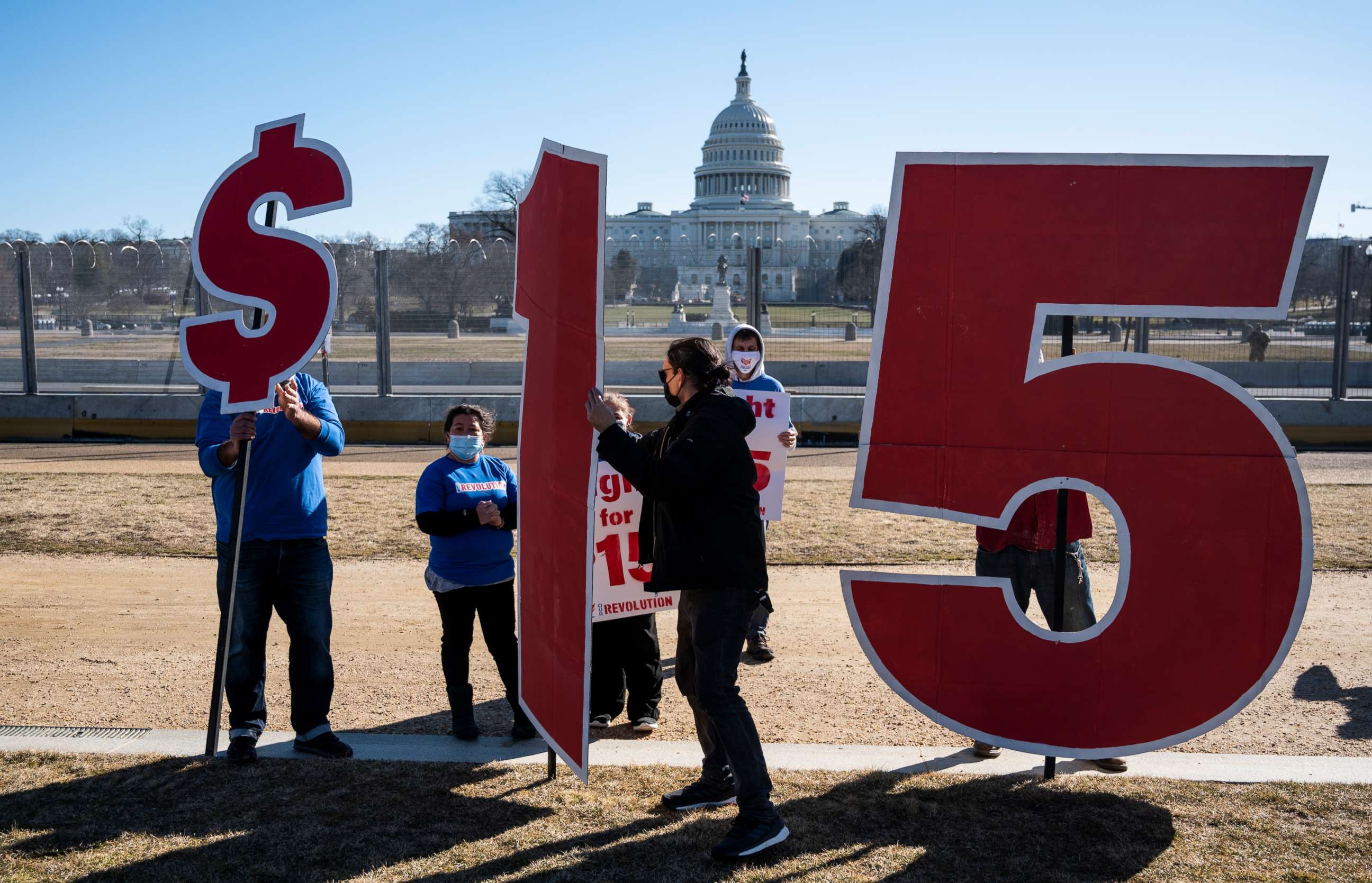 PHOTO: Activists hold signs outside the Capitol complex in Washington on Feb. 25, 2021, to call on Congress to pass the $15 federal minimum wage hike proposed as part of the COVID relief bill.