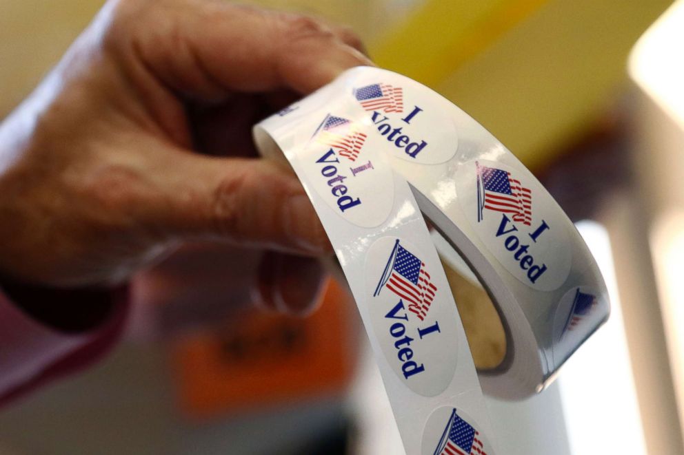 PHOTO: Poll manager Larry Greer hands holds a roll of "I Voted" stickers given each person after voting in a runoff election Tuesday, Nov. 27, 2018 in Ridgeland, Miss.