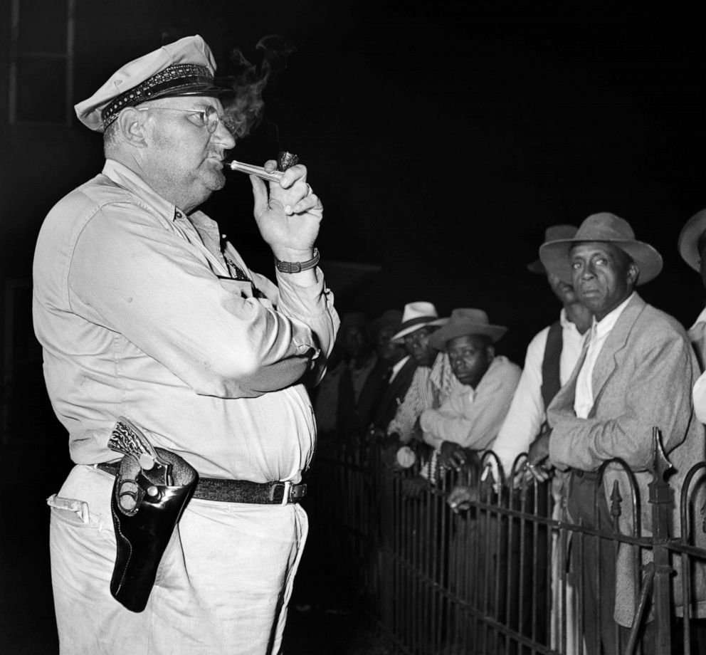 PHOTO: A sheriff stands smoking a pipe in front of a crowd at a voting registration site in 1946 in Mississippi.