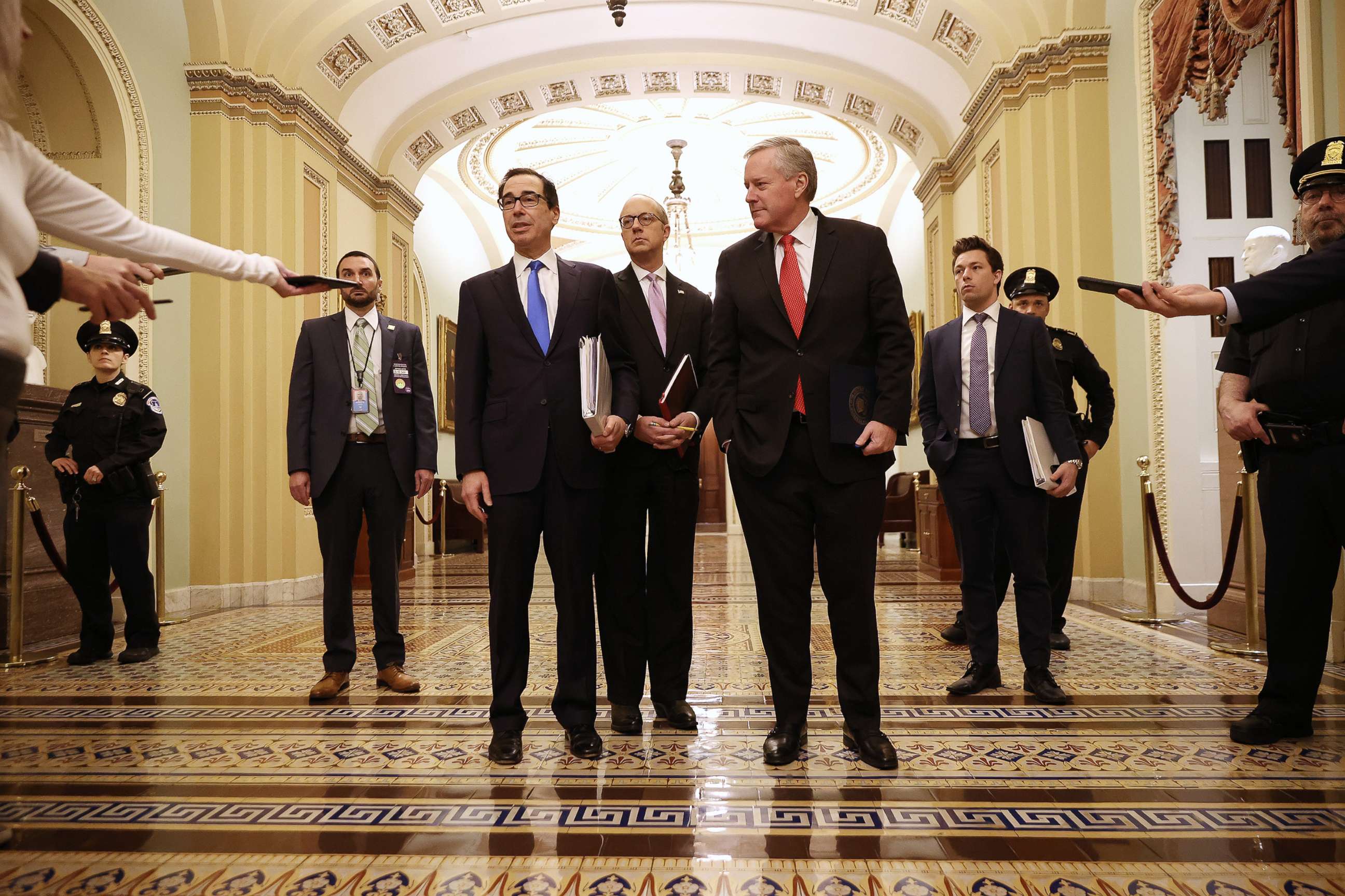 PHOTO: Treasury Secretary Steven Mnuchin talks briefly with reporters after arriving at the Capitol with White House Director of Legislative Affairs Eric Ueland and White House Chief of Staff Mark Meadows, March 24, 2020 in Washington.