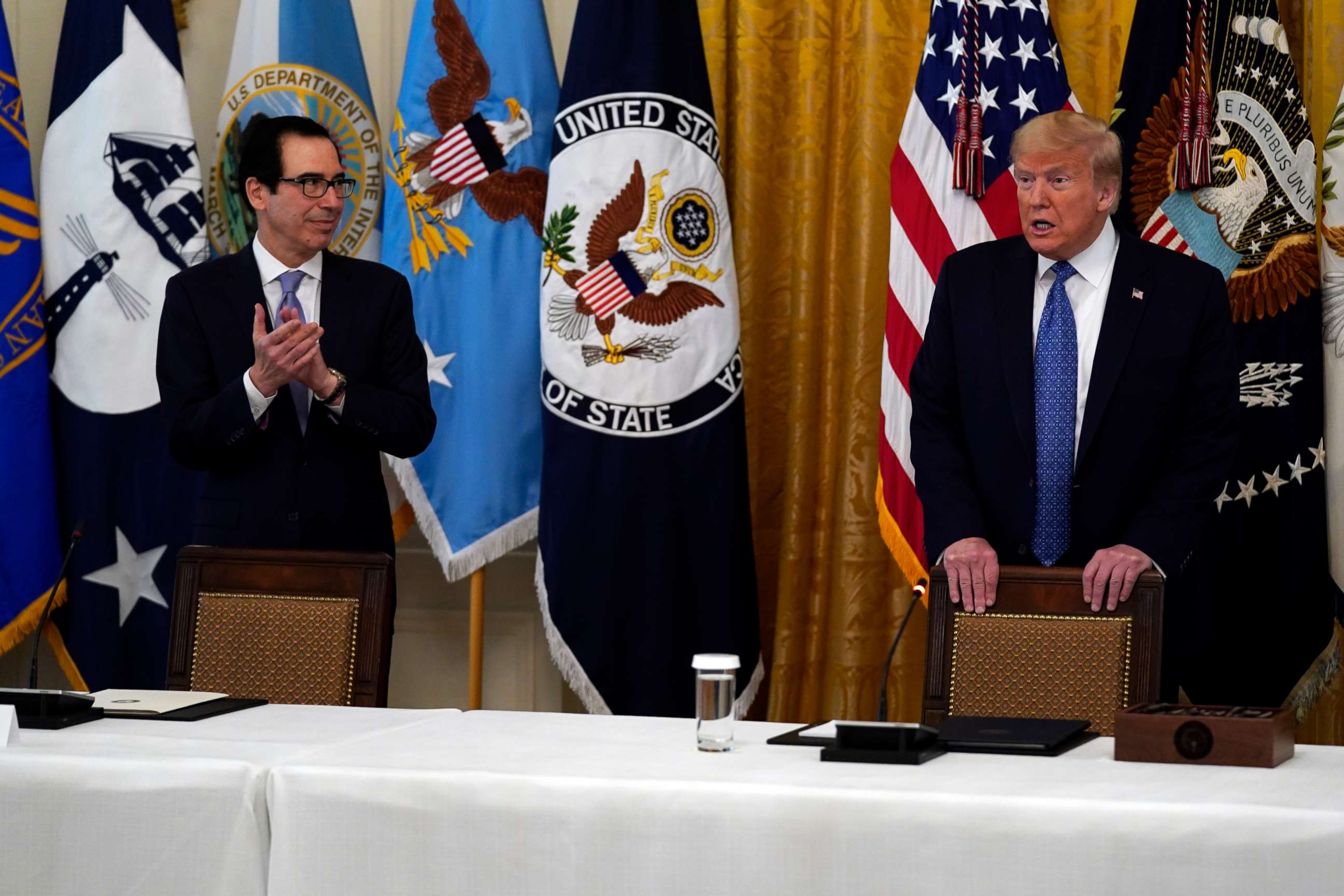 PHOTO: President Donald Trump arrives for a Cabinet Meeting in the East Room of the White House, May 19, 2020, in Washington, as Treasury Secretary Steven Mnuchin applauds.