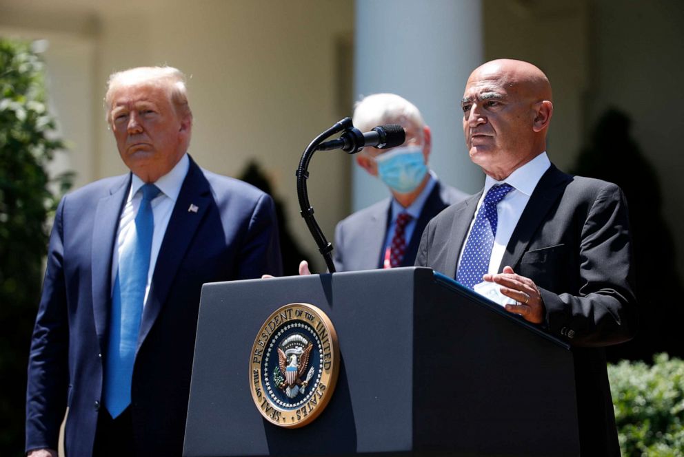 PHOTO: President Donald Trump, left, listens as Moncef Slaoui, a former GlaxoSmithKline executive, speaks about the coronavirus in the Rose Garden of the White House, May 15, 2020, in Washington.