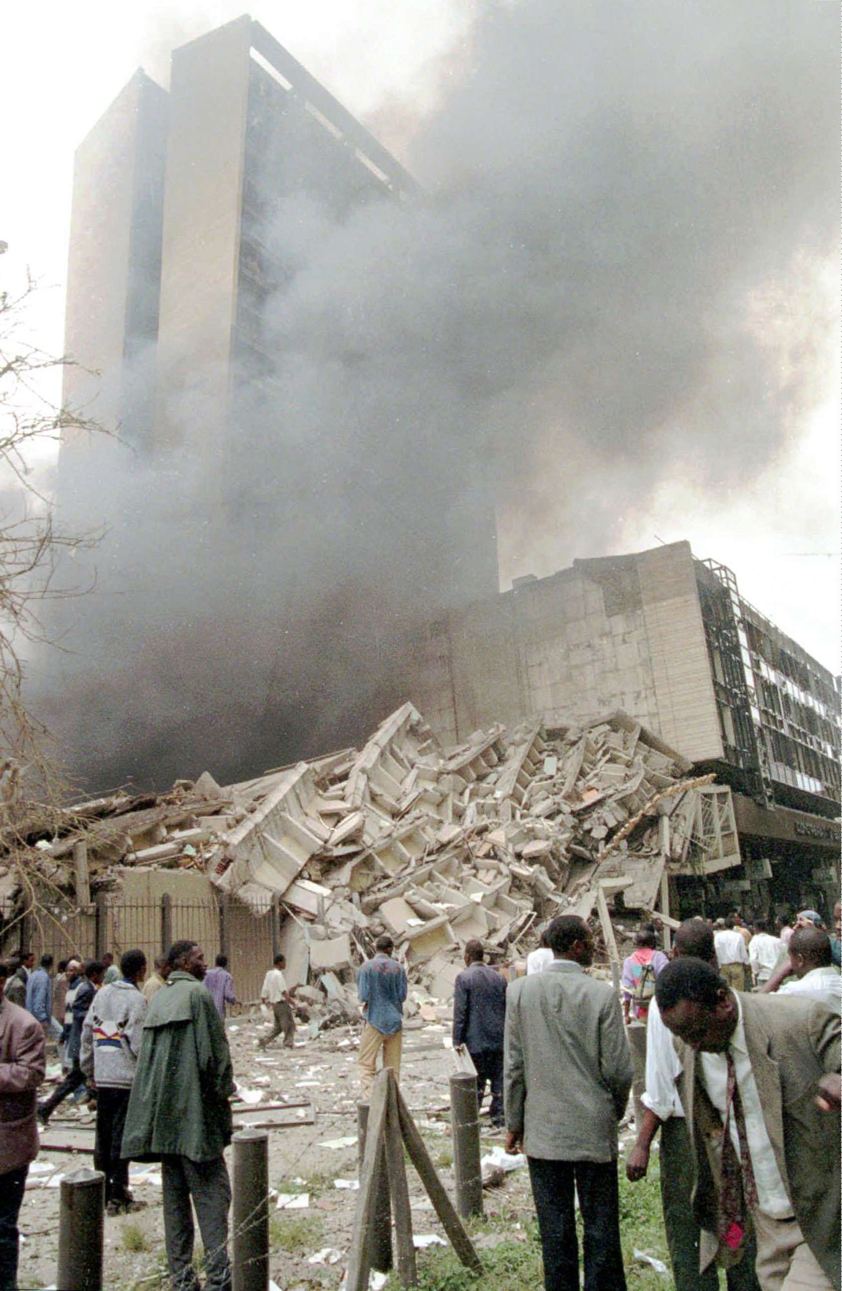 PHOTO: Passersby look at damaged buildings in Nairobi, Kenya, after a huge explosion ripped apart a building in the Kenyan capital, heavily damaging the American Embassy and killing at least 40 people and injuring dozens, Aug. 7, 1998.