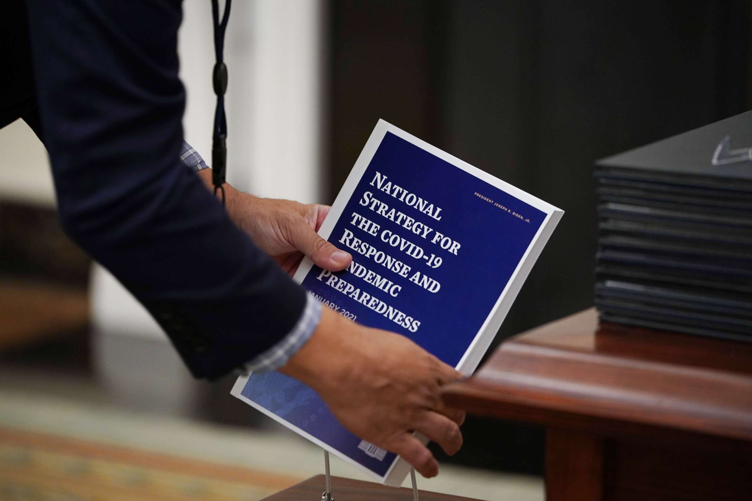 PHOTO: An aide collects copies of the National Strategy for COVID-19 before President Joe Biden speaks in the State Dining Room of the White House in Washington, Jan. 21, 2021.