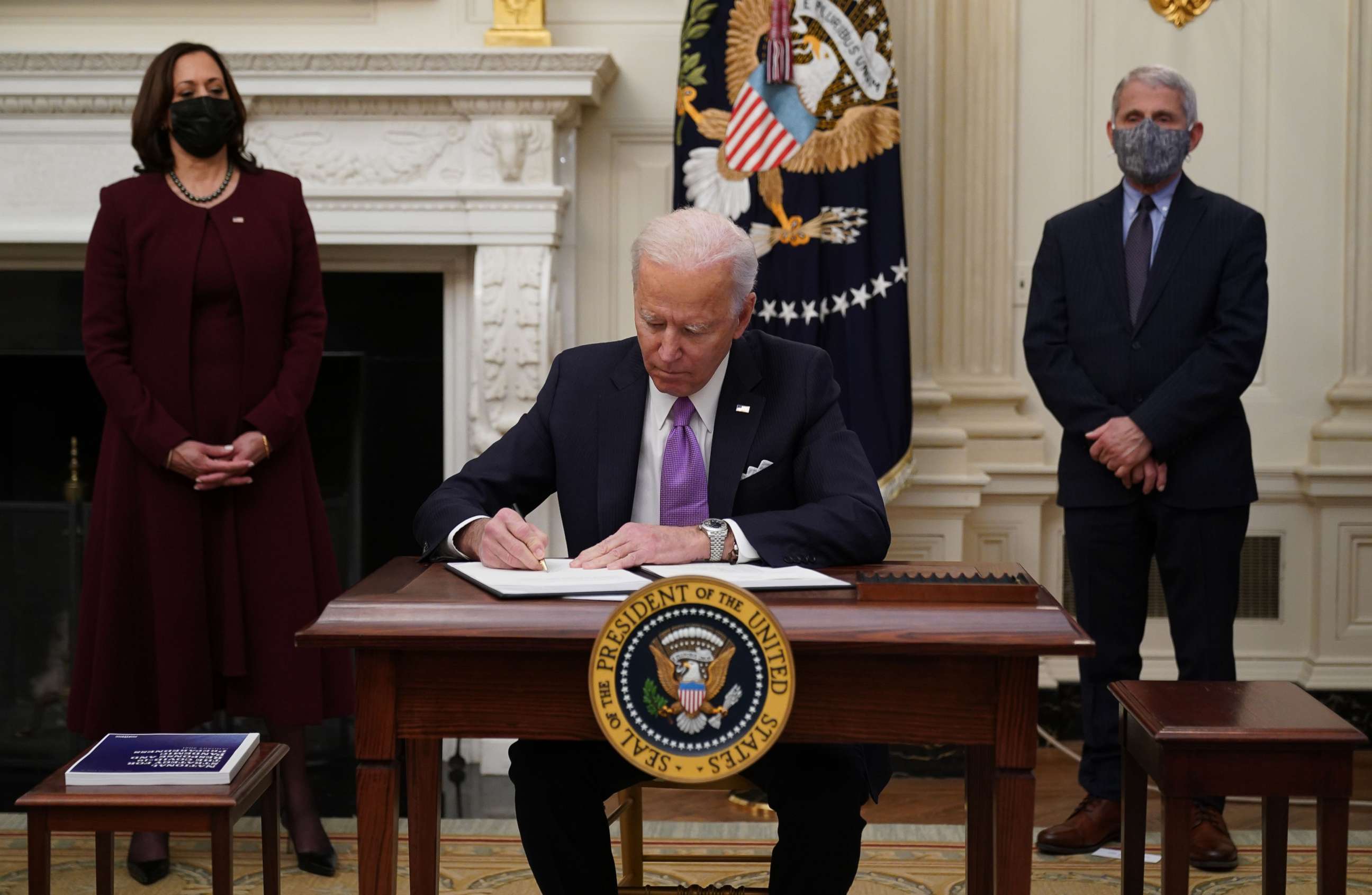 PHOTO: President Joe Biden signs executive orders as part of the COVID-19 response as Vice President Kamala Harris and Director of NIAID Anthony Fauci look on in the State Dining Room of the White House in Washington, D.C., Jan. 21, 2021.