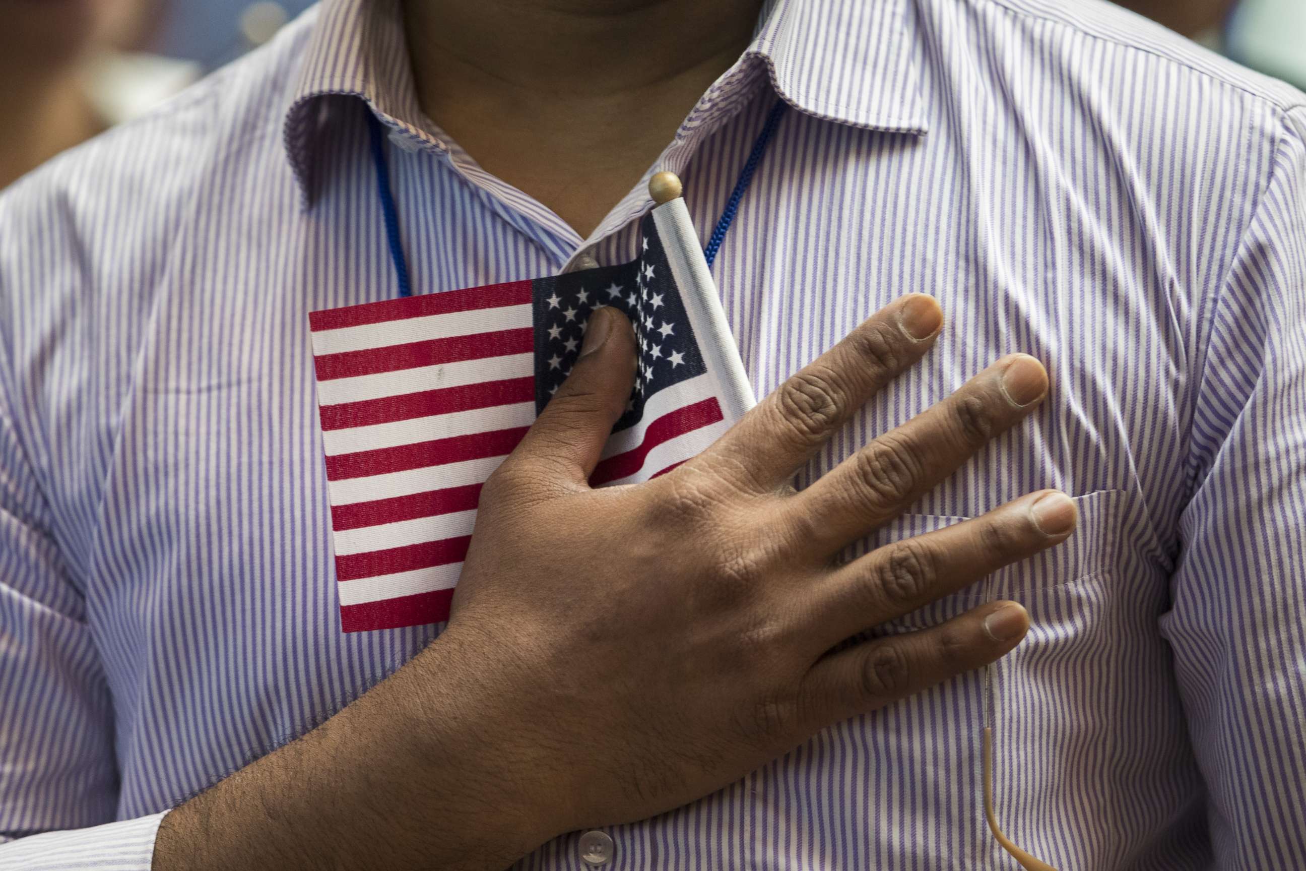 PHOTO: A new U.S. citizen holds a flag to his chest during the Pledge of Allegiance during a naturalization ceremony at the New York Public Library, July 3, 2018, in New York.