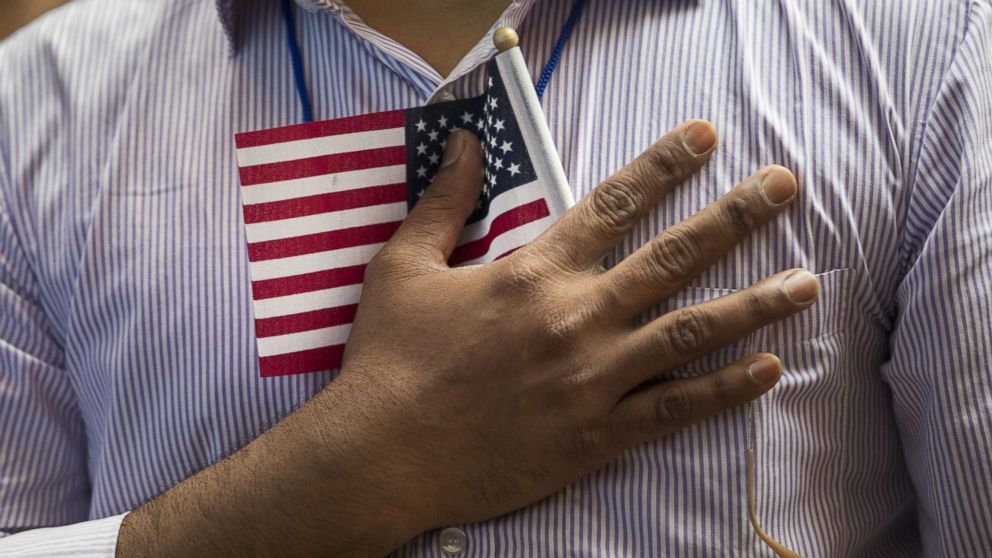 PHOTO: A new U.S. citizen holds a flag to his chest during the Pledge of Allegiance during a naturalization ceremony at the New York Public Library, July 3, 2018, in New York.
