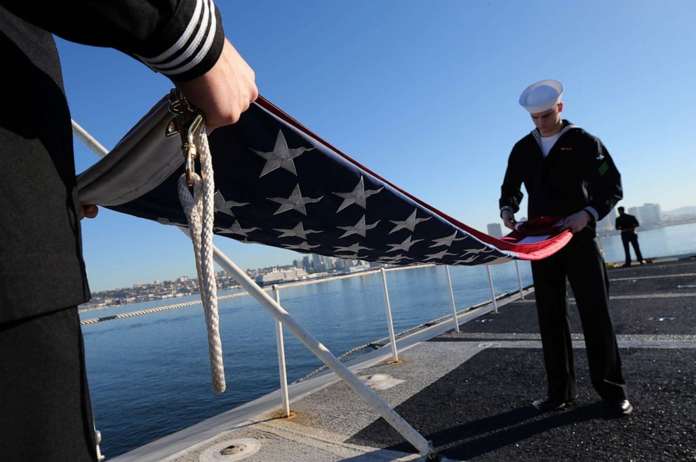 PHOTO: Navy sailors fold the flag on the flight deck of the USS Nimitz (CVN 68) aircraft carrier, Jan. 18, 2020 in Coronado, Calif. 