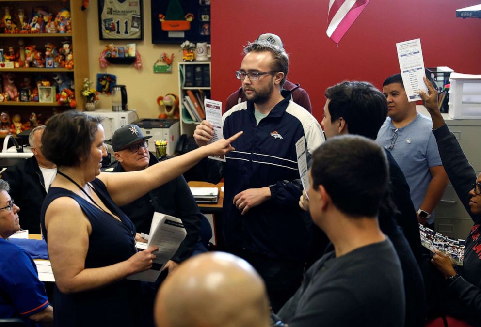 Democratic Caucus voters hold up their Presidential Preference Cards to indicate who they are voting for at start of the first alignment with particular presidential candidates inside the caucus at Liberty High School in Henderson, Nevada, Feb. 22, 2020.