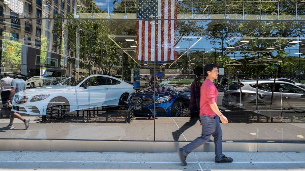 PHOTO: A person walks by a car dealership on June 10, 2022 in New York.