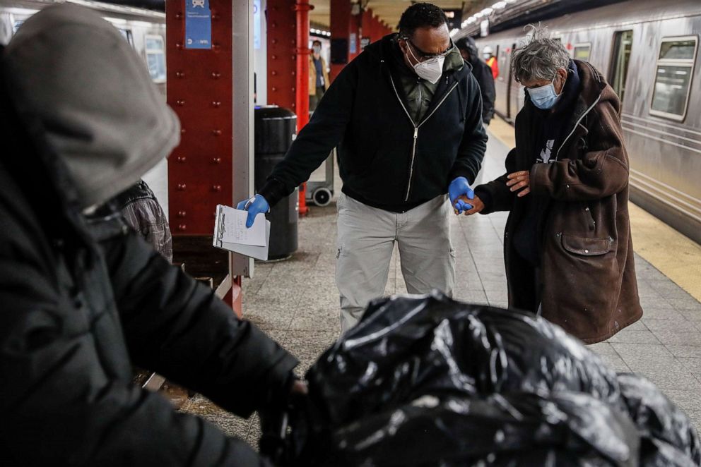 PHOTO: A homeless man is given assistance by a homeless outreach worker in the 207th Street A-train station, April 30, 2020, in New York.