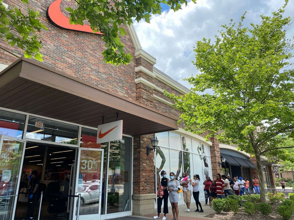 PHOTO: People line up outside a Nike outlet at the Promenade Shopping Center in Little Rock, Ark. while the store operates at a reduced capacity on May 20, 2020.