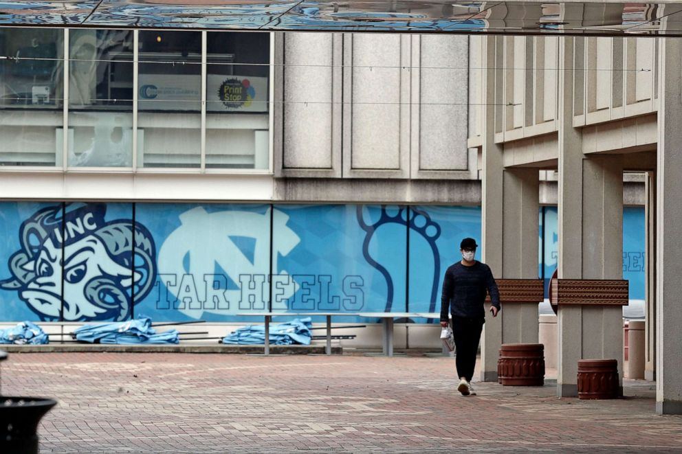 PHOTO: In this March 18, 2020 file photo, a pedestrian walks through campus at the University of North Carolina in Chapel Hill, N.C.