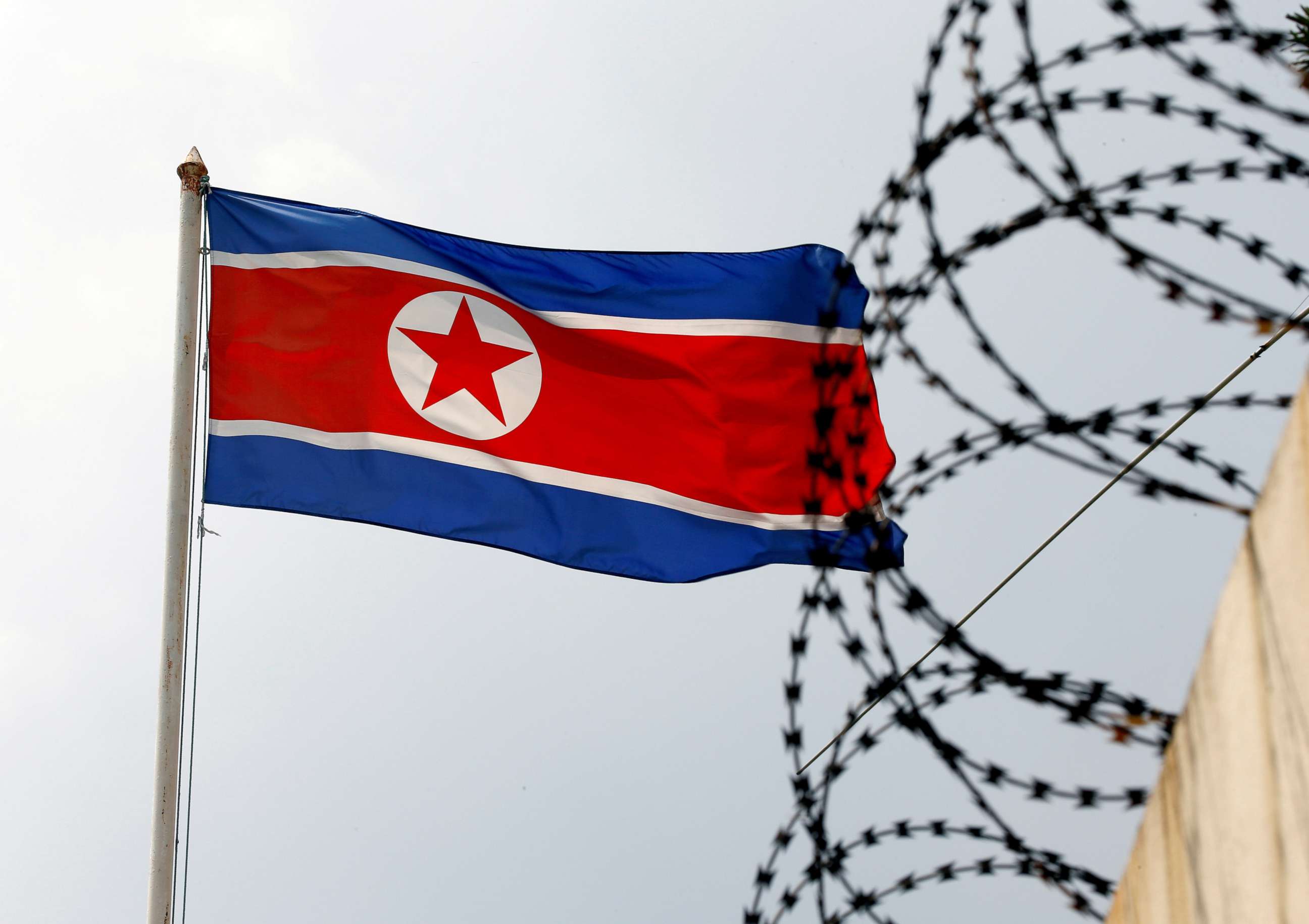 PHOTO: A North Korea flag flies near concertina wire.