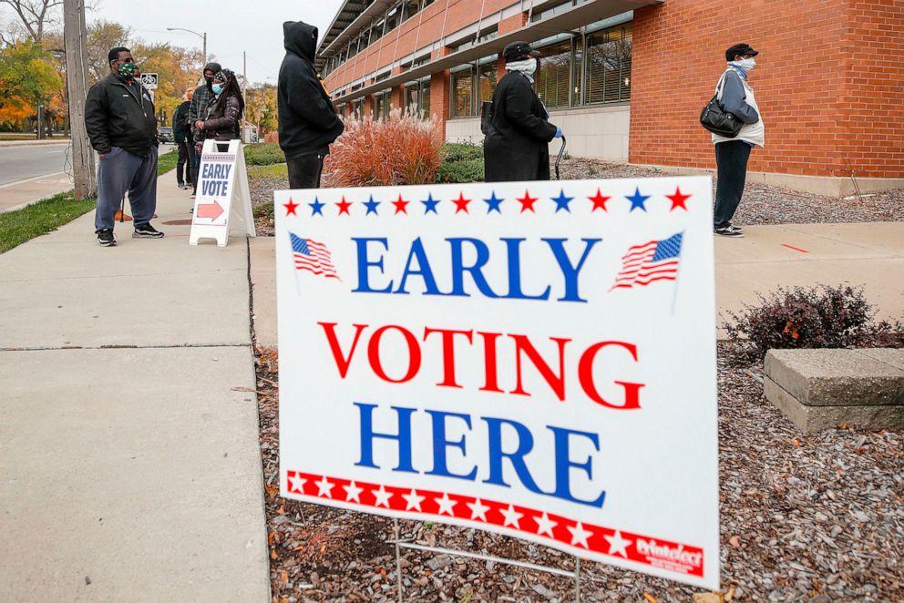 PHOTO: People wait in line outside the Washington Park Library to cast their ballots on the first day of in-person early voting in Milwaukee.