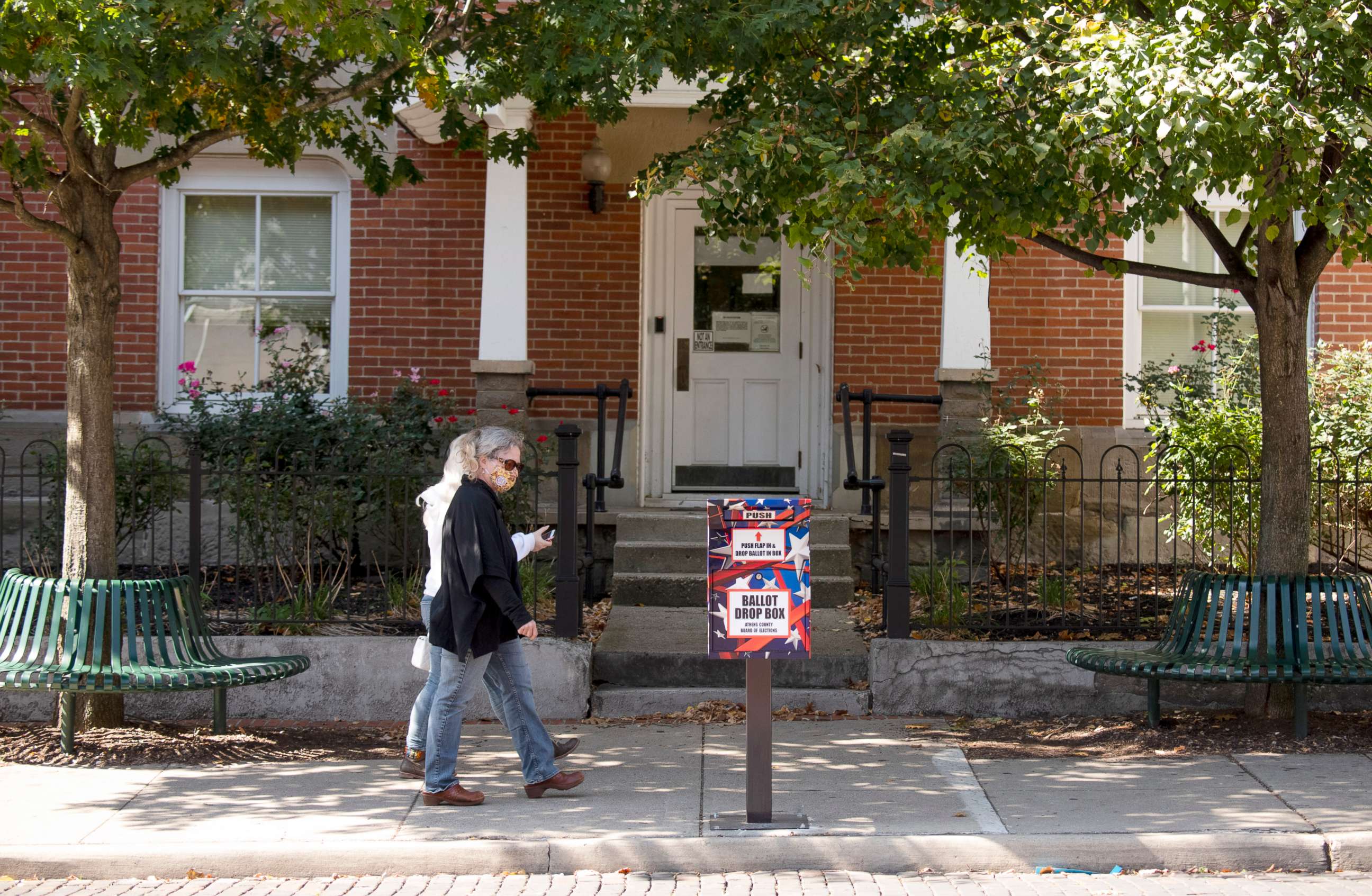 PHOTO: People walk past a ballot drop box outside the Athens County Board of Elections Office in Athens, Ohio, Oct. 6, 2020. 