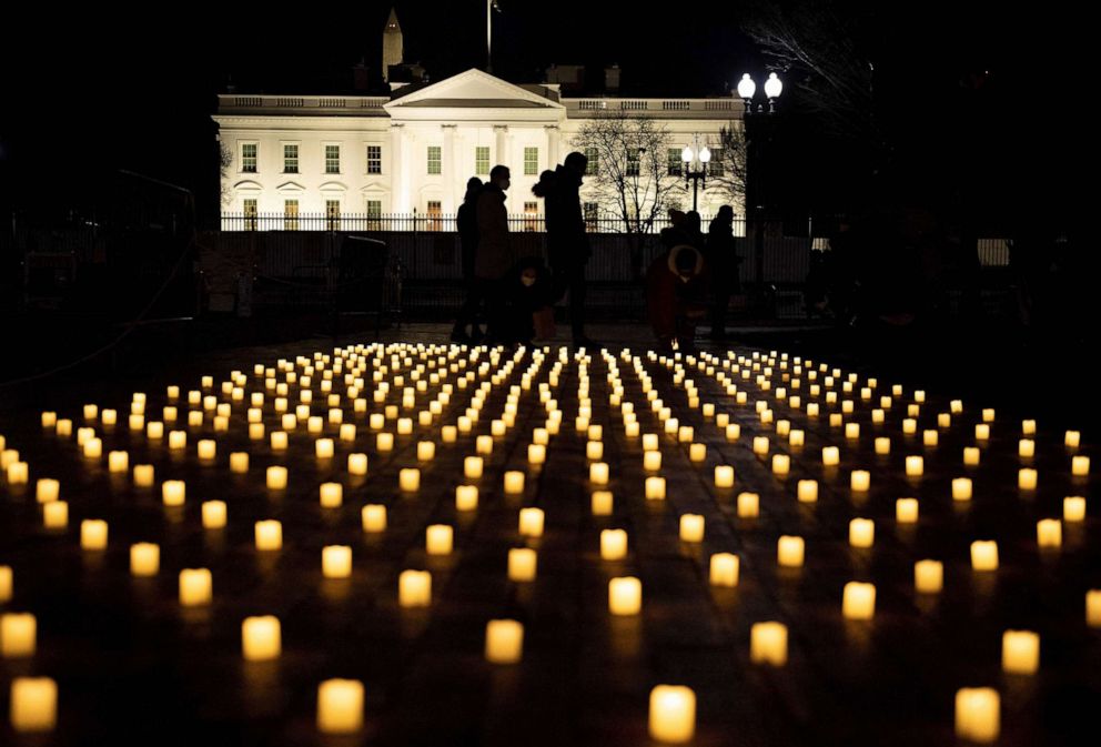 PHOTO: People walk past electric candles from a vigil in Lafayette Park for nurses who died during the COVID-19 pandemic, Jan. 13, 2022, in Washington, D.C.