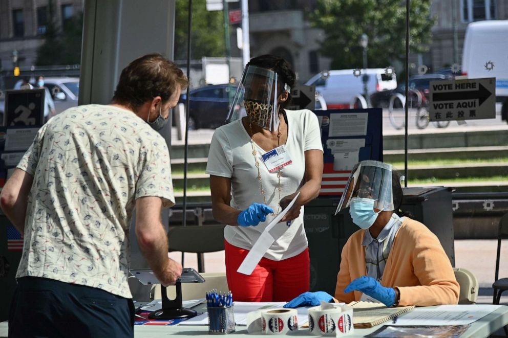 PHOTO: Board of Election employees and volunteers wearing PPE (personal protective equipment) assist voters at the Brooklyn Museum polling site for the New York Democratic presidential primary elections on June 23, 2020 in New York City.