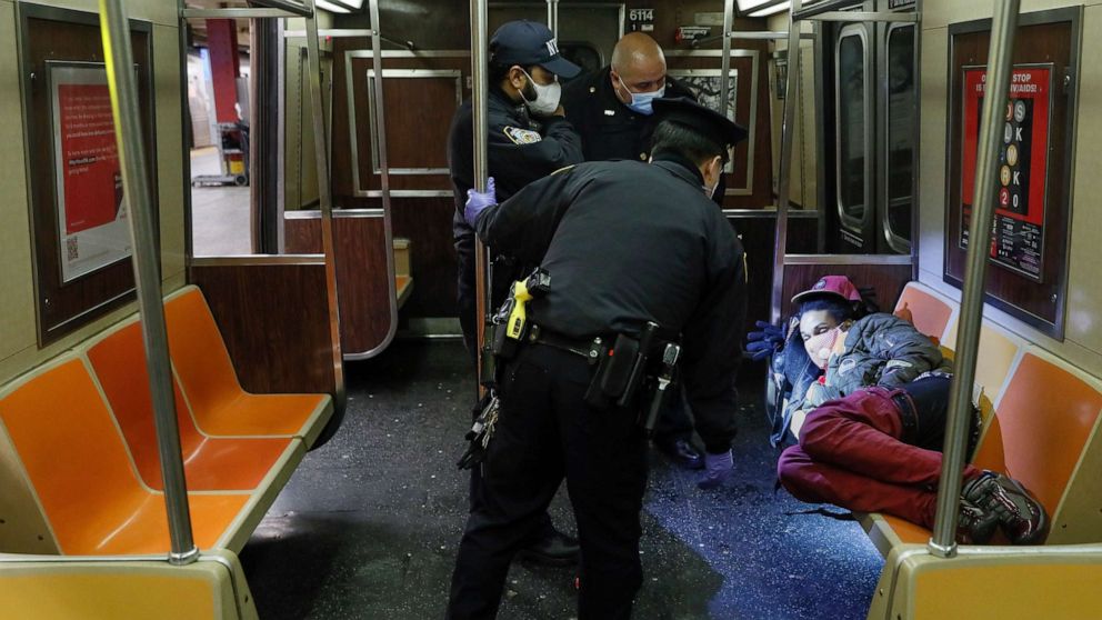 PHOTO: NYPD and MTA officers wake up a sleeping passenger before directing him to exit the 207th Street A-train station, April 30, 2020, in New York City.