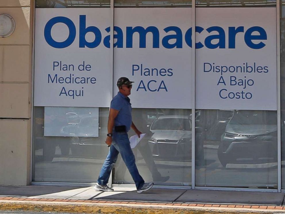PHOTO: A person walks by a health care insurance office in Hialeah, Fla. on July 27, 2017.