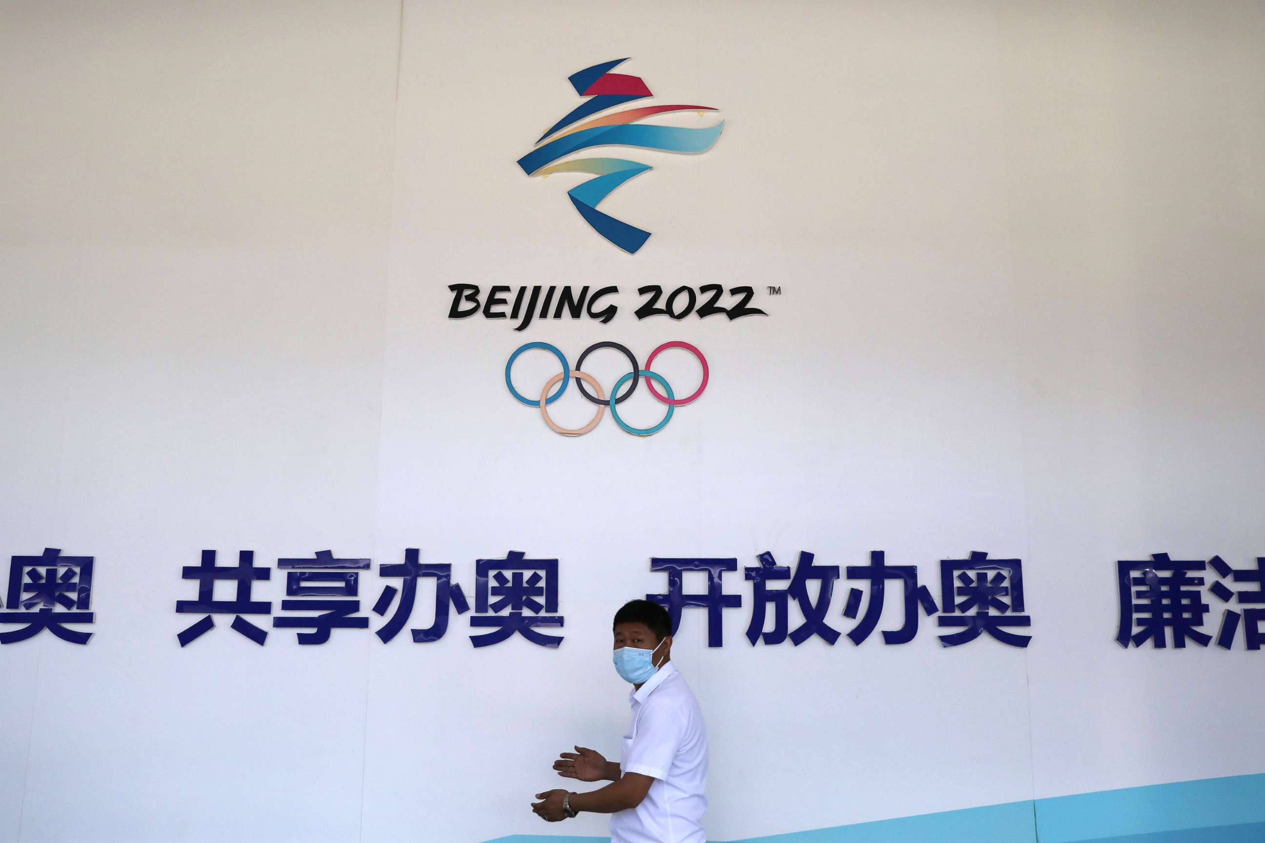 PHOTO:A man walks past a board with a sign of Beijing 2022 Winter Olympic Games at an exhibition hall during an organized media tour to venues of the Games in Zhangjiakou, Hebei province, China, July 14, 2021. 