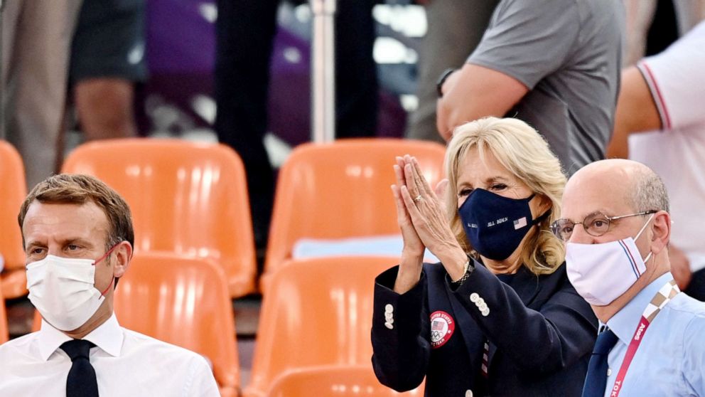 PHOTO: First Lady Jill Biden applauds next to French President Emmanuel Macron  while attending the Women's first round 3x3 basketball match between US and France at the Aomi Urban Sports Park in Tokyo, on July 24, 2021.