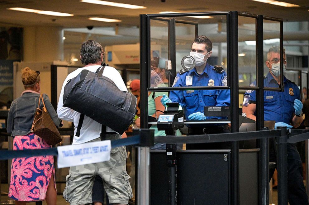 PHOTO: A TSA agent wears a face mask to help curb the spread of COVID-19 while checking passengers at a security checkpoint at Orlando International Airport, on May 28, 2021, in Orlando, Fla.