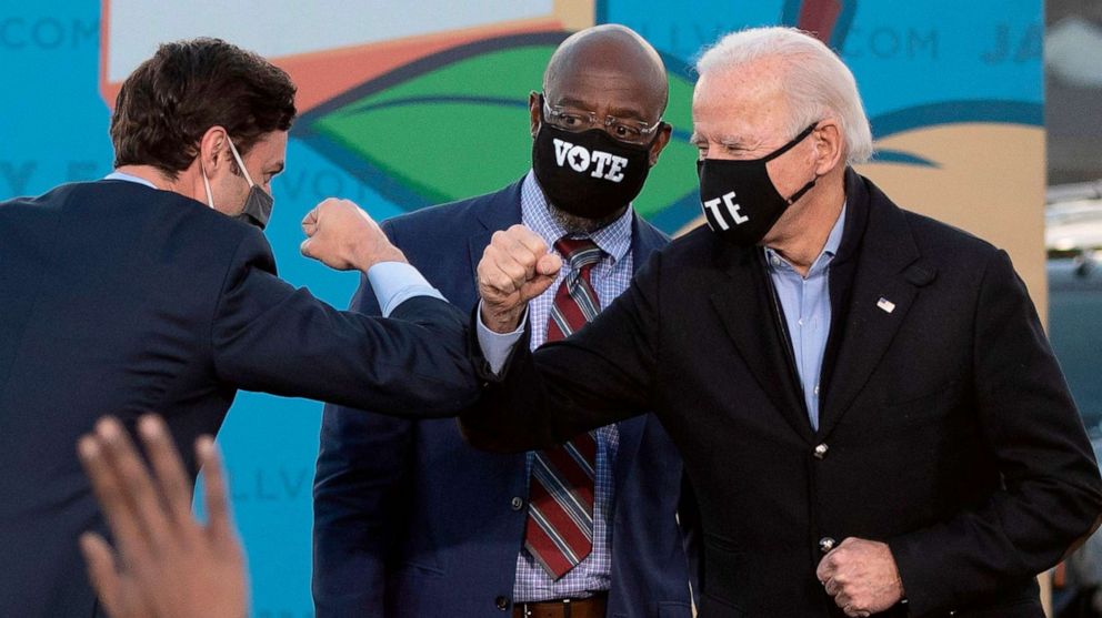 PHOTO: In this Jan. 4, 2021, file photo, Democratic candidates for Senate Jon Ossoff, Raphael Warnock, cener, and President-elect Joe Biden bump elbows on stage during a rally outside Center Parc Stadium in Atlanta.