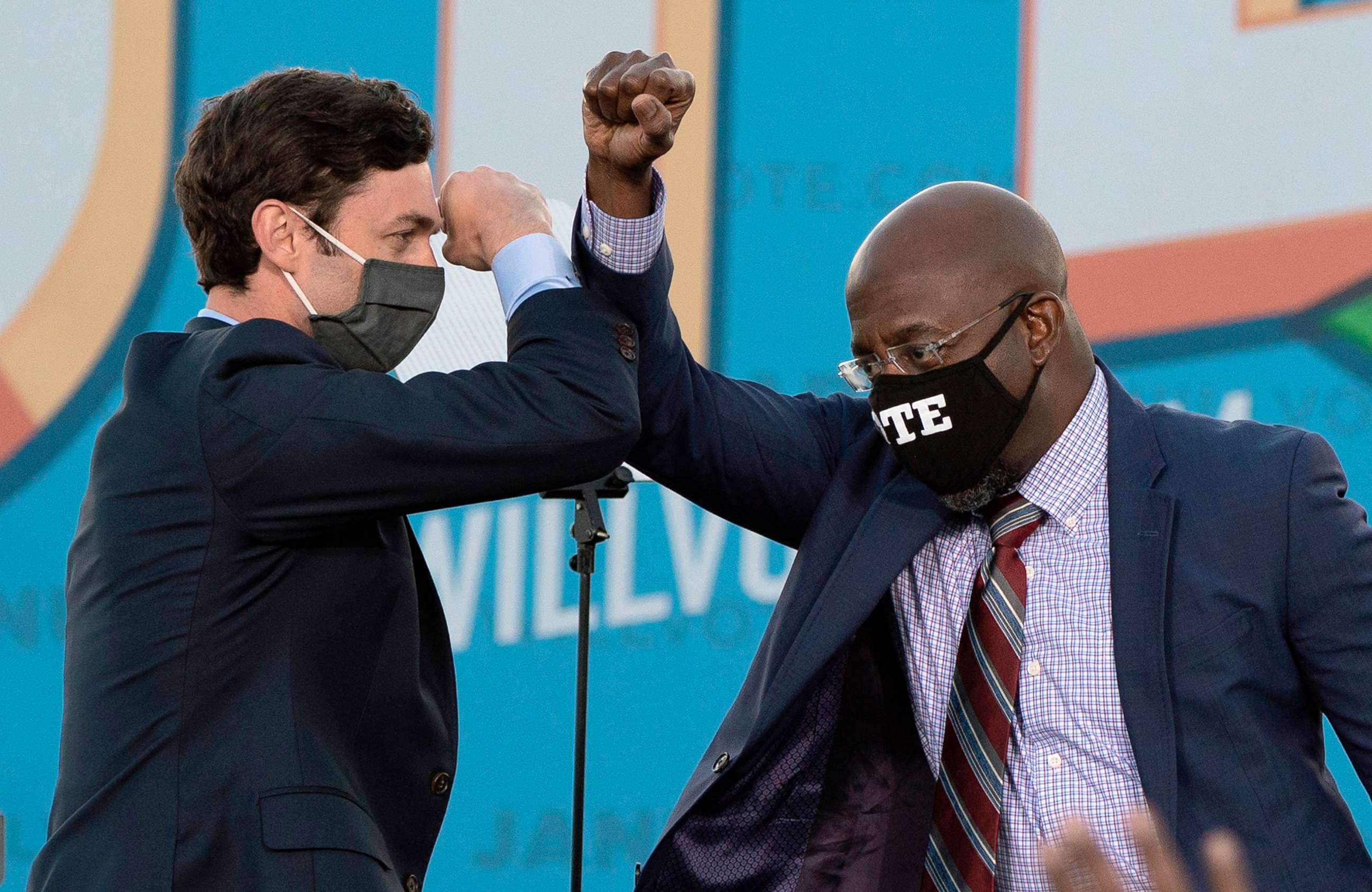PHOTO: Democratic candidates for Senate Jon Ossoff, left, and Raphael Warnock bump elbows on stage during a rally with President-elect Joe Biden outside Center Parc Stadium in Atlanta, Jan. 4, 2021.