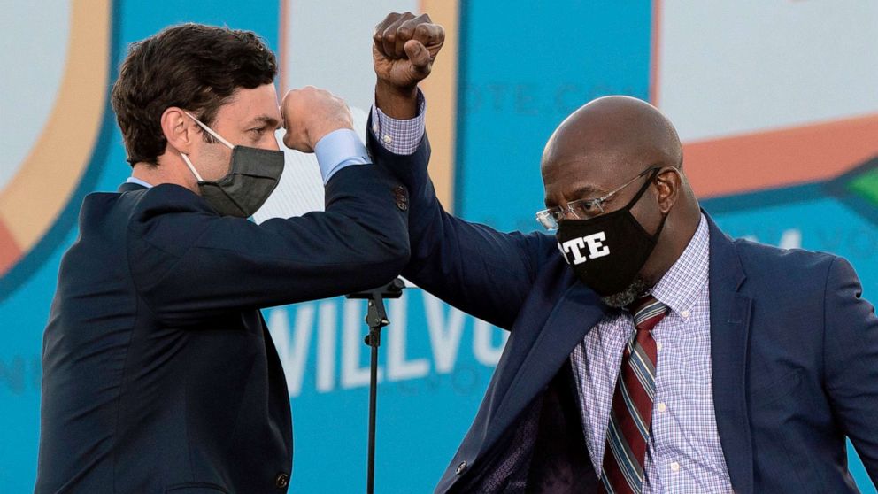 PHOTO: Democratic candidates for Senate Jon Ossoff, left, and Raphael Warnock bump elbows on stage during a rally with President-elect Joe Biden outside Center Parc Stadium in Atlanta, Jan. 4, 2021.