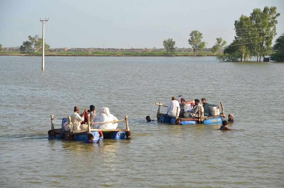 PHOTO: Displaced people wade through floodwaters after heavy monsoon rains, Sept. 18, 2022, in Usta Mohammad, Pakistan. 