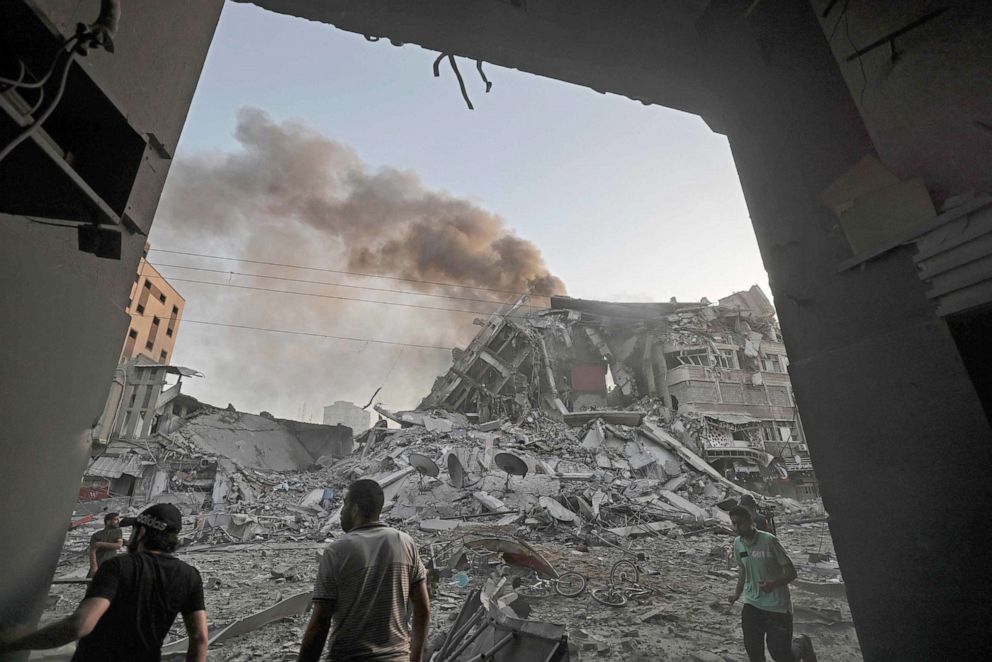 PHOTO: People gather amidst the rubble in front of Al-Sharouk tower that collapses after being hit by an Israeli air strike, in Gaza City, May 12, 2021. 