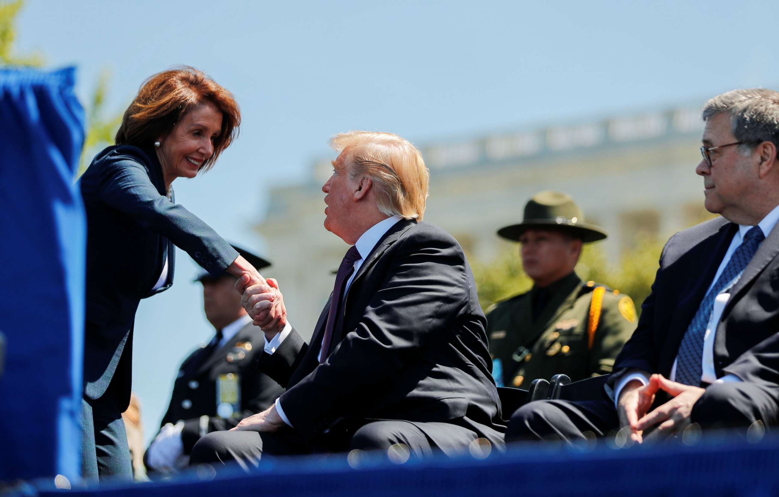 PHOTO: President Donald Trump shakes hands with Speaker of the House Nancy Pelosi while Attorney General William Barr looks on as they all attend the 38th Annual National Peace Officers Memorial Service on Capitol Hill, May 15, 2019. 
