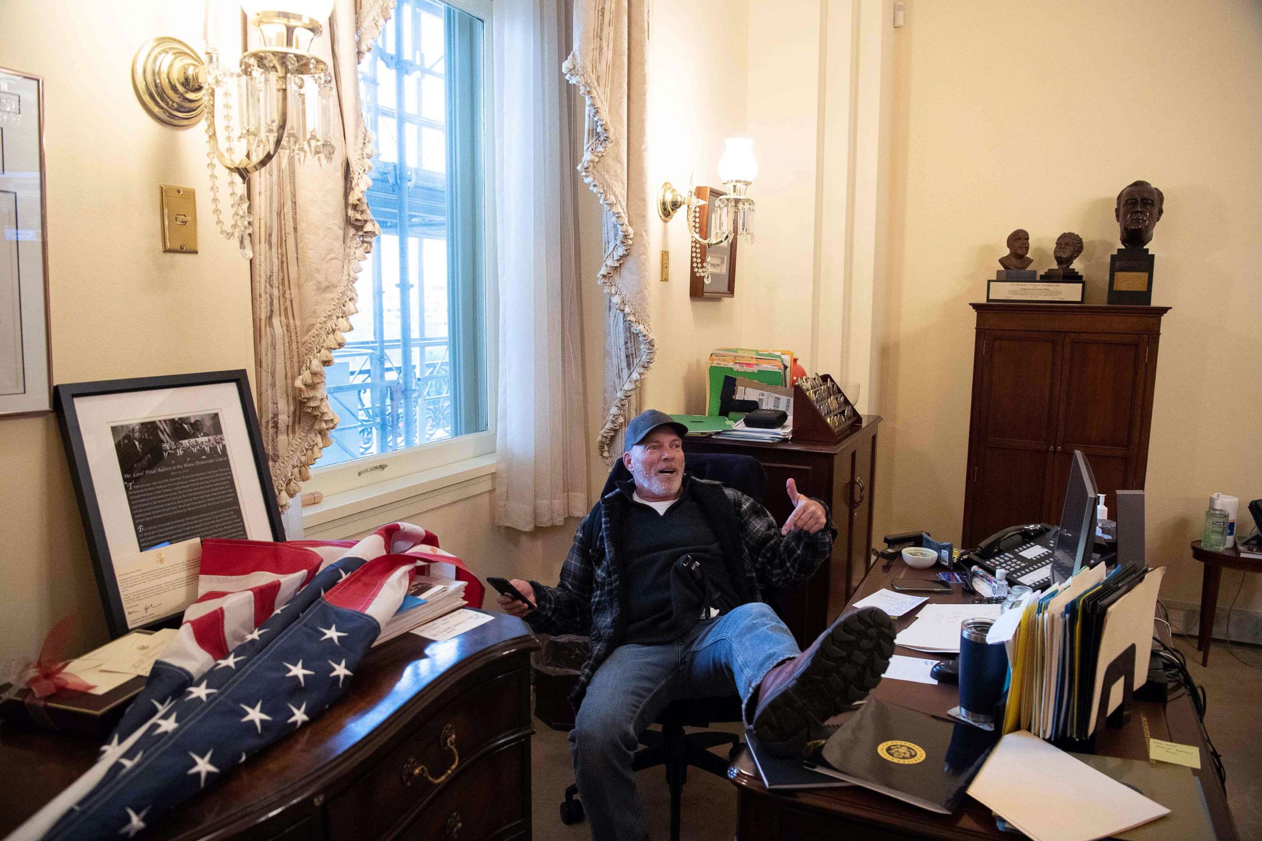 PHOTO: A supporter of President Donald Trump sits inside the office of Speaker of the House Nancy Pelosi after protesters broached the U.S. Capitol in Washington, D.C., Jan. 6, 2021, as Congress met to certify the a 2020 presidential election.