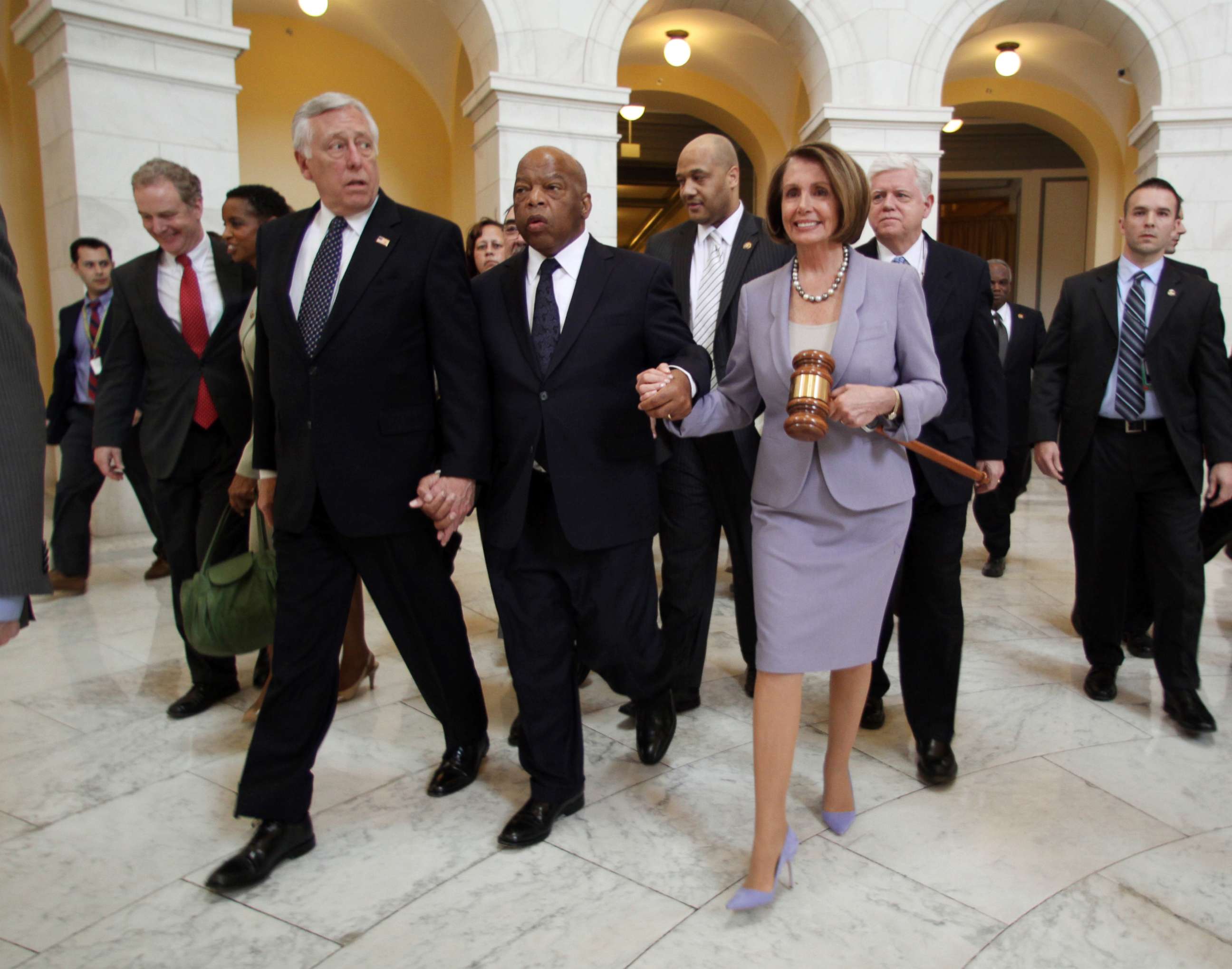 PHOTO: House Speaker Nancy Pelosi holds a large gavel as she walks through the Cannon Rotunda after a Democratic Caucus, along with from left, are Reps. Steny Hoyer, John Lewis, and John Larson, March 21, 2010 on Capitol Hill in Washington.