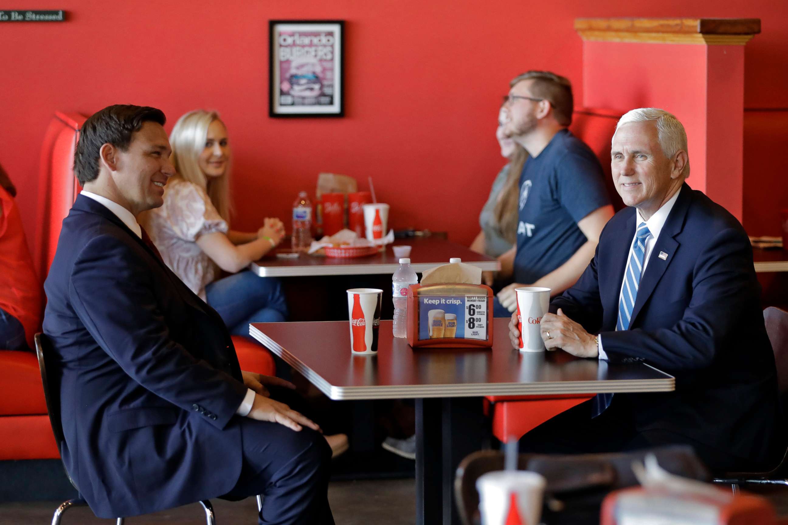 PHOTO: Vice President Mike Pence, right, talks to Florida Gov. Ron DeSantis as they wait for their lunch at Beth's Burger Bar, May 20, 2020, in Orlando, Fla. 