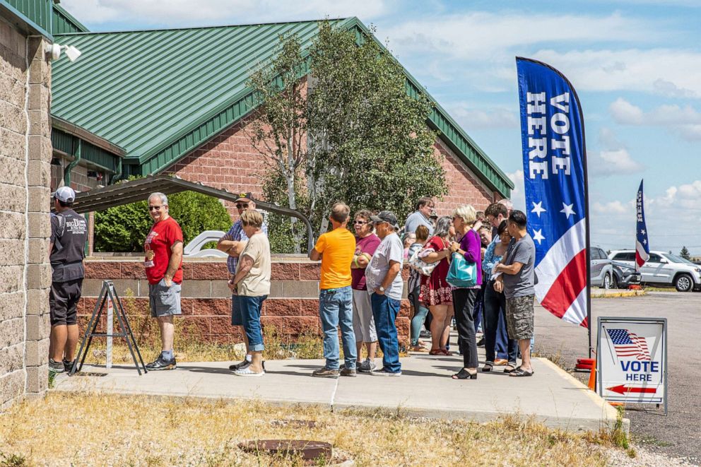PHOTO: Voters wait in line to cast ballots outside a polling location at North Christian Church in Cheyenne, Wyo., on Aug. 16, 2022. 