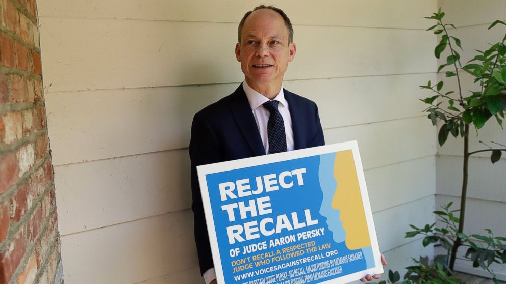 In this May 15, 2018 file photo, Judge Aaron Persky poses for a photo with a sign opposing his recall in Los Altos Hills, Calif. Northern California voters are deciding on Tuesday, June 5 whether to remove Persky from office