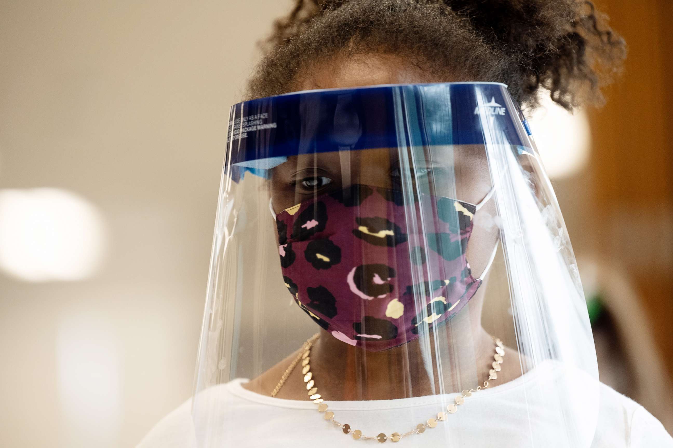 PHOTO: An elementary school student wears a face shield and mask while standing in the cafeteria in Louisville, Ky., March 17, 2021.