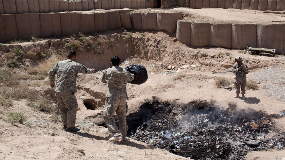 PHOTO: Two interpreters for Bravo troop dump their trash in the base's "burn pit" in the Zhari District of Kandahar Province which is a stronghold of the Taliban in Afghanistan, April 1, 2012. 