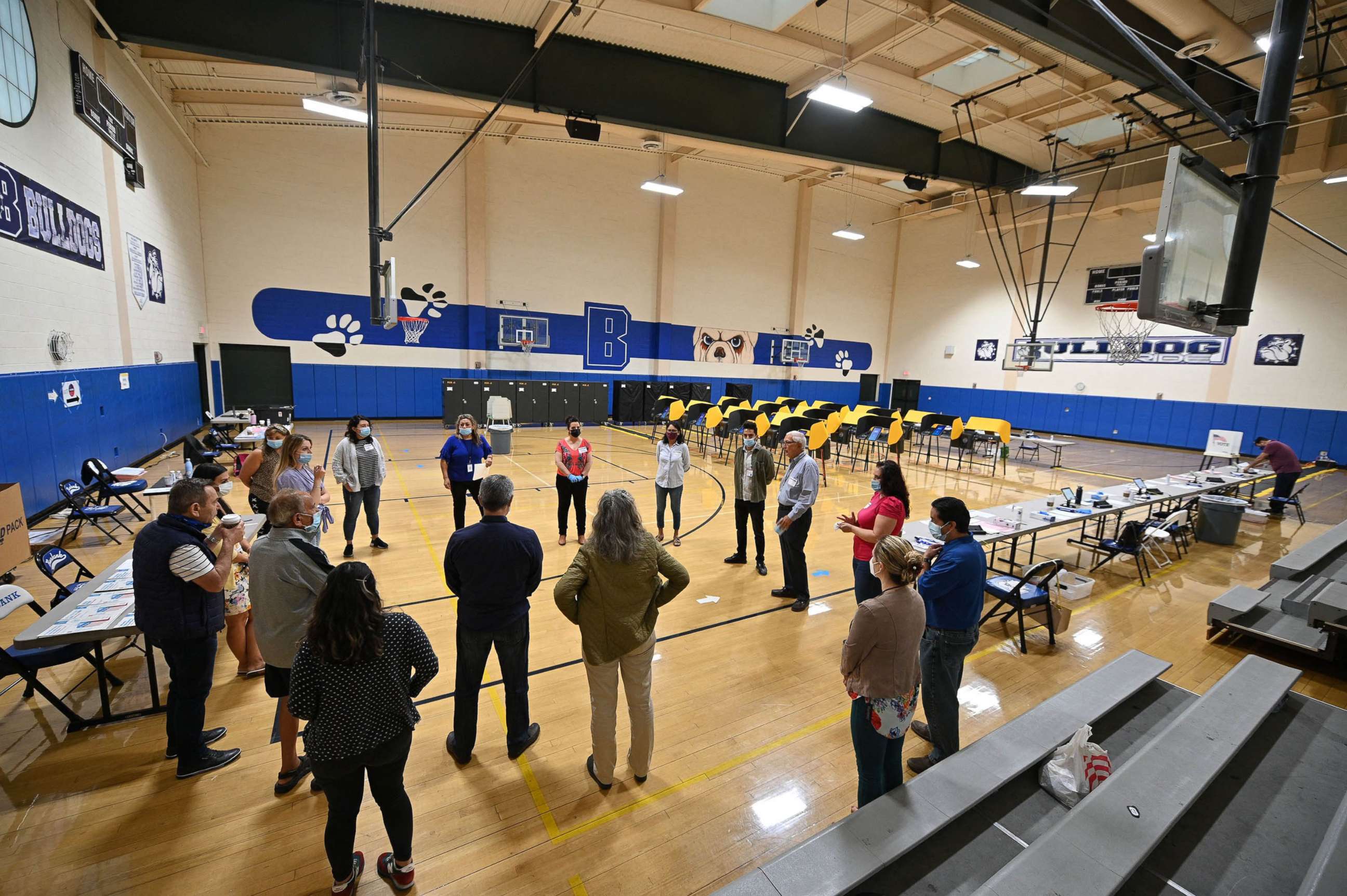 PHOTO: Poll workers wearing masks and gloves have a meeting before doors open a polling station at Burbank High School in Burbank, Calif., Sept. 14, 2021. 